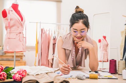 Attractive Asian female fashion designer working in home office, a Person Photo by Ministocker