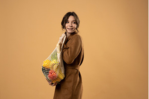 Woman in brown coat holding eco mesh, a Person Photo by volodymyrshtun13795