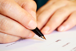 woman signing document with pen