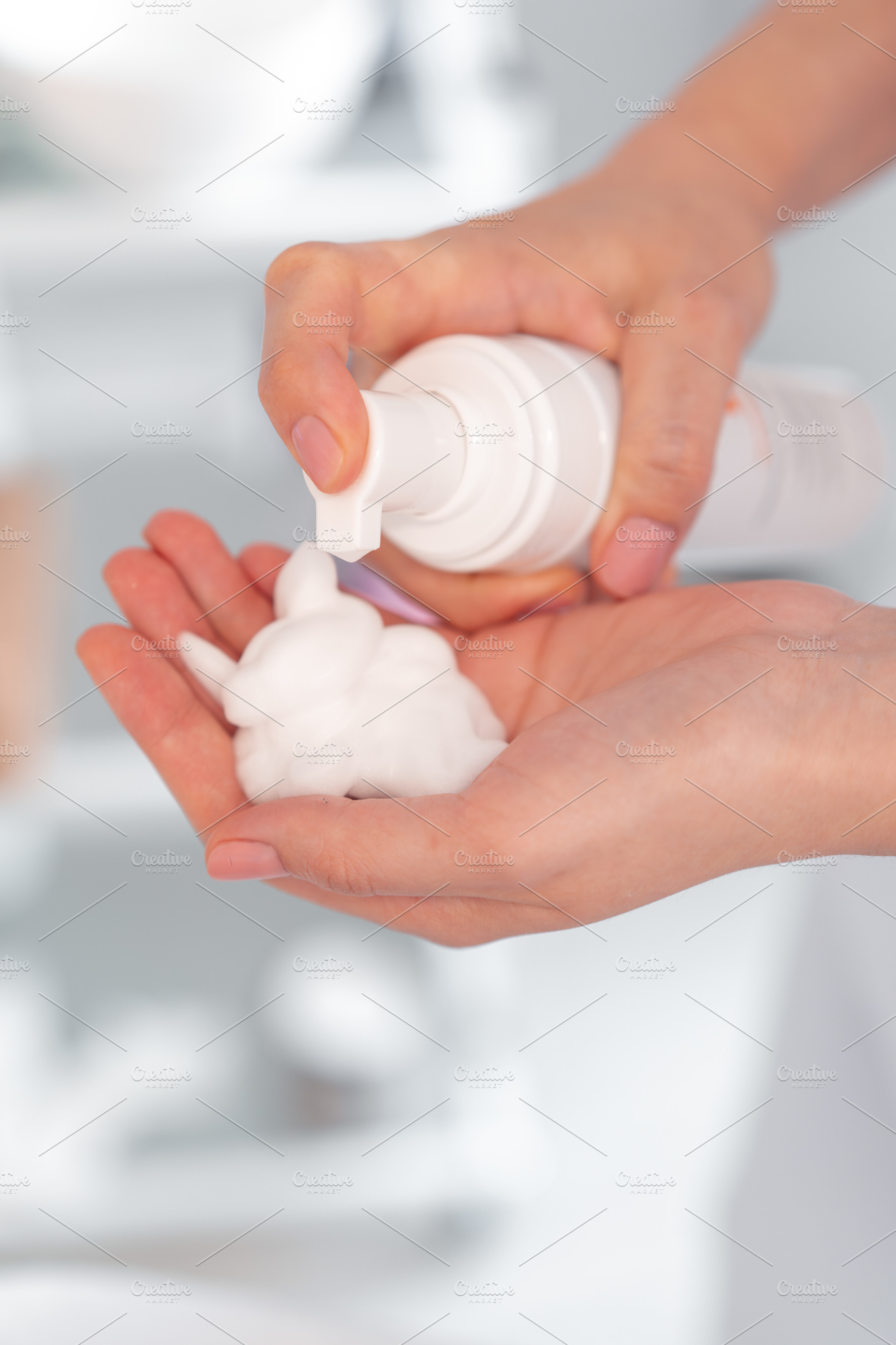 Crop hands of cosmetologist removing foam cream from bottle in hand, a Photo by andreonegin market