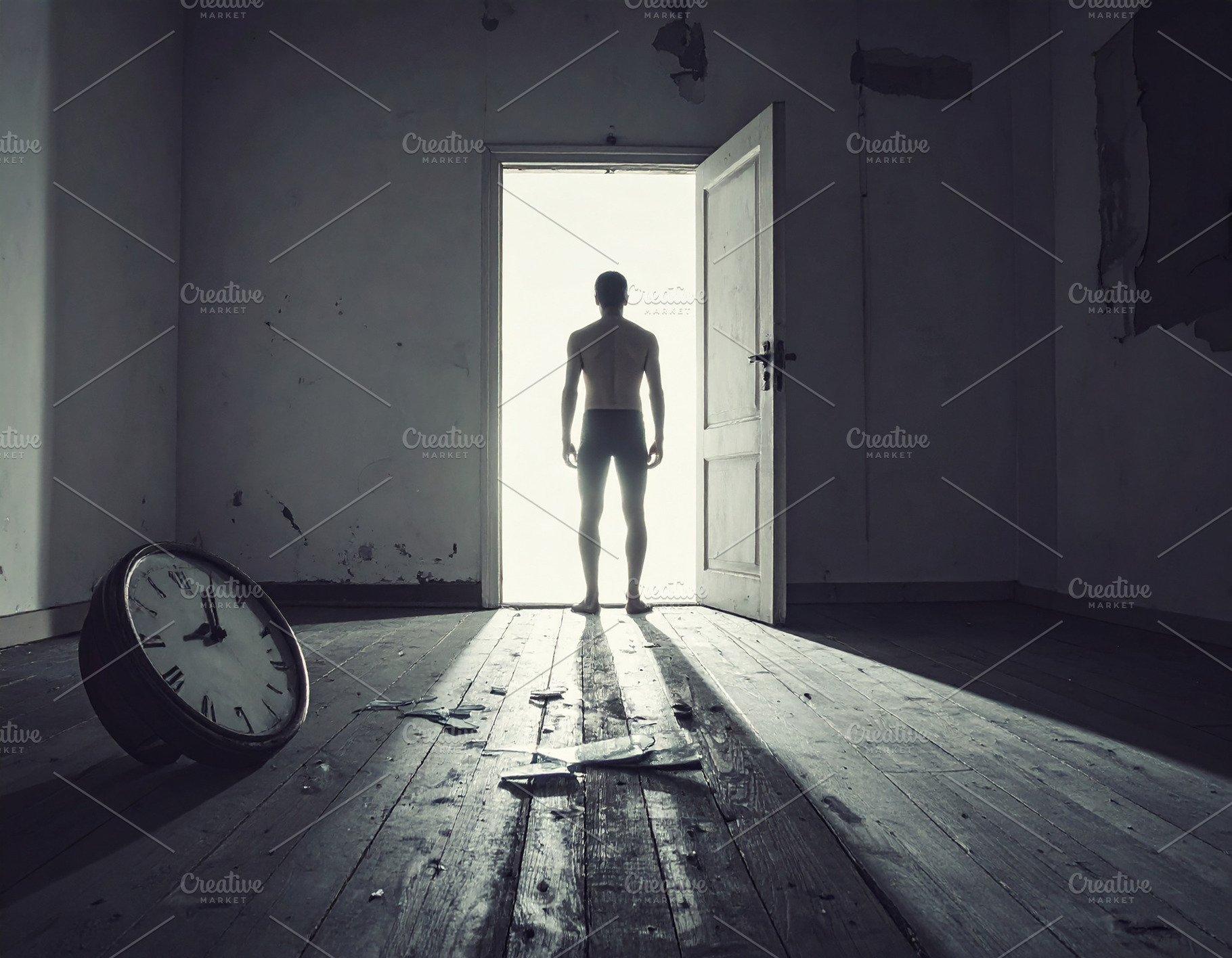 Man standing in dark room looking towards bright open doorway, a Person Photo by DanFLCreativo