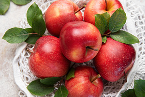 Fresh red apples with leaves in reusable shopping bag on table, a Food & Drink Photo by Olena Rudo