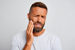 Middle-aged man with hand on cheek in pain because of a toothache, a Health & Medical Photo by AlyaAnd
