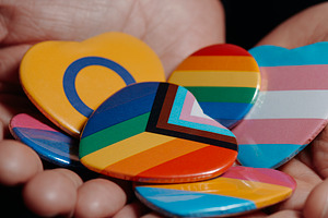 badges with different LGBTQ flags in his hands, a Photo by Nito