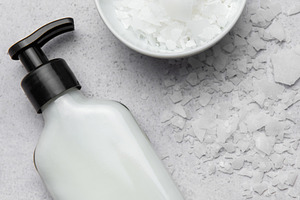 Magnesium flakes beside a dispenser for body cream on gray backg, a Health & Medical Photo by Olena Rudo