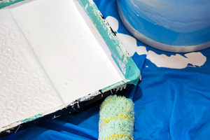 Paint roller, tray and bucket with white paint on blue protective sheet, an Industrial Photo by etorres69
