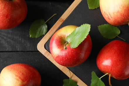 Apples and cutting board on wooden background, top view, a Food & Drink Photo by AtlasStudio