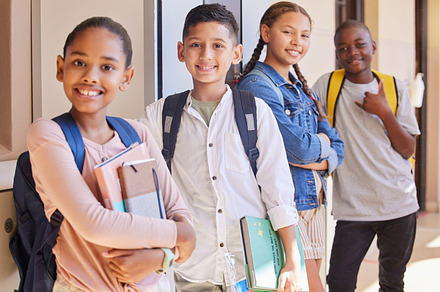 School, friendship and portrait of a group of children standing with backpack and books in hallway. Education, diversity and knowledge, happy young students smile together outside classroom in USA., a Photo by Peopleimages.com
