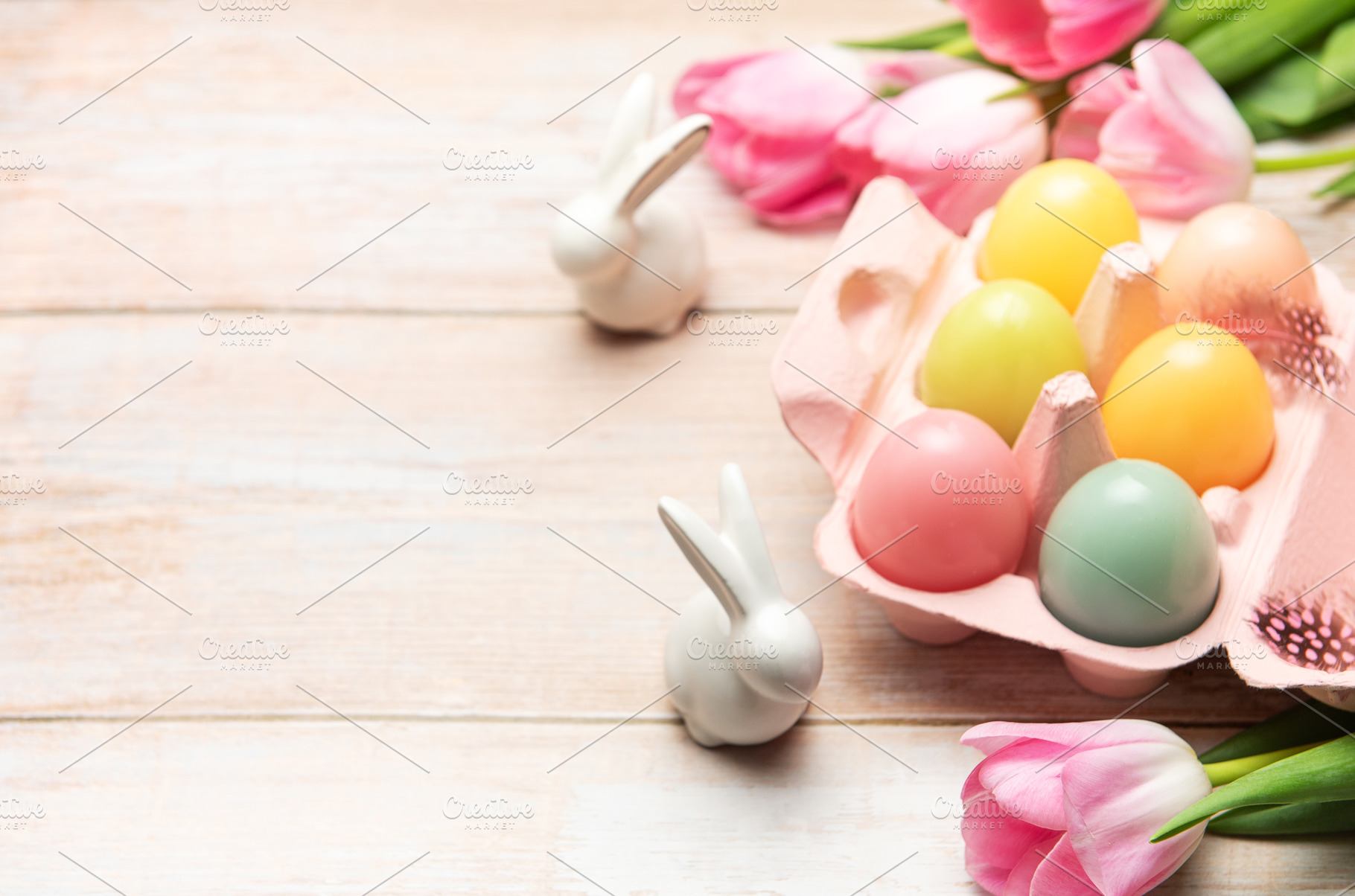 Easter eggs with ceramic bunnies and pink tulips decorating wood, a Holiday Photo by Olena Rudo