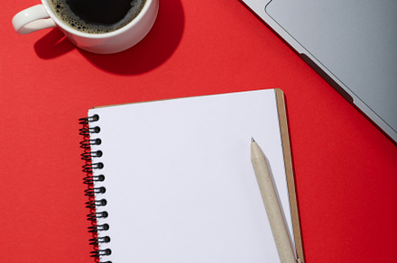 Notebook, cup of coffee and laptop on red background, a Business Photo by AtlasStudio