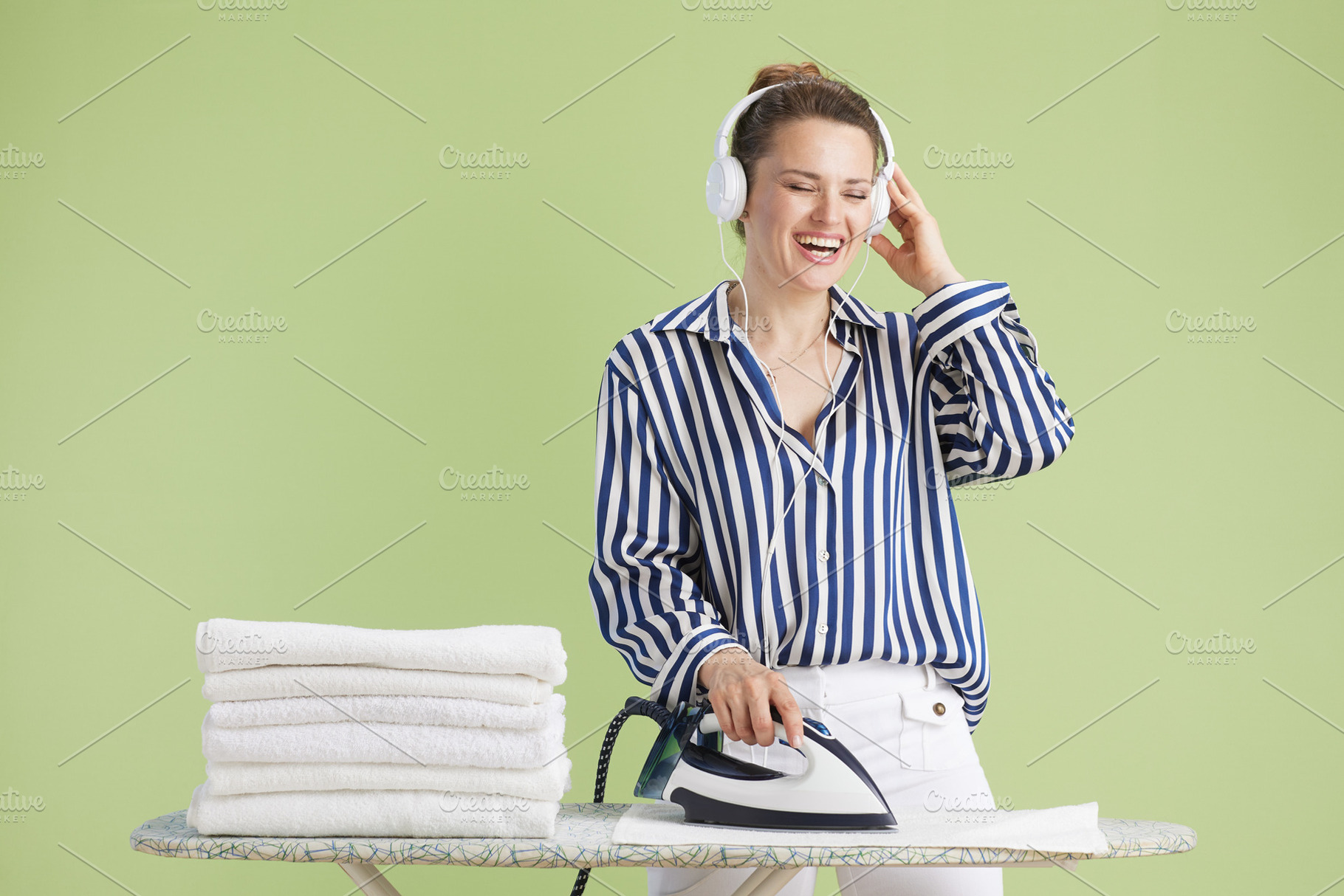 Woman listening to music while ironing towels, a Person Photo by Alliance Images
