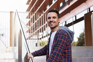 Young man smiling on outdoor stairs near modern building, a Person Photo by RF Images