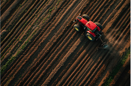 Red tractor plowing fertile soil on, an Industrial Photo by Ylivdesign