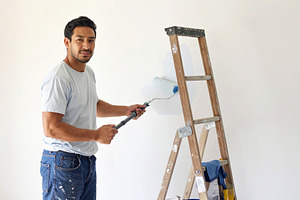 House painter working indoors, painting a wall with a roller, a Person Photo by DanFLCreativo