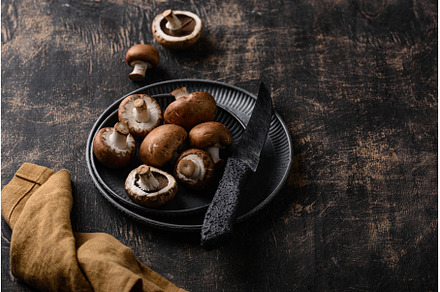Raw champignon mushrooms on black, a Food & Drink Photo by Yulia Furman