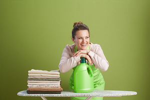Content woman with laundry detergent on ironing board, a Person Photo by Alliance Images