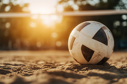 Volleyball resting on sandy beach at sunset with warm golden light, a Sports & Recreation Photo by AlyaAnd