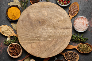 Spices around a round wooden board. Turmeric, cloves, anise, pep, a Food & Drink Photo by ndanko