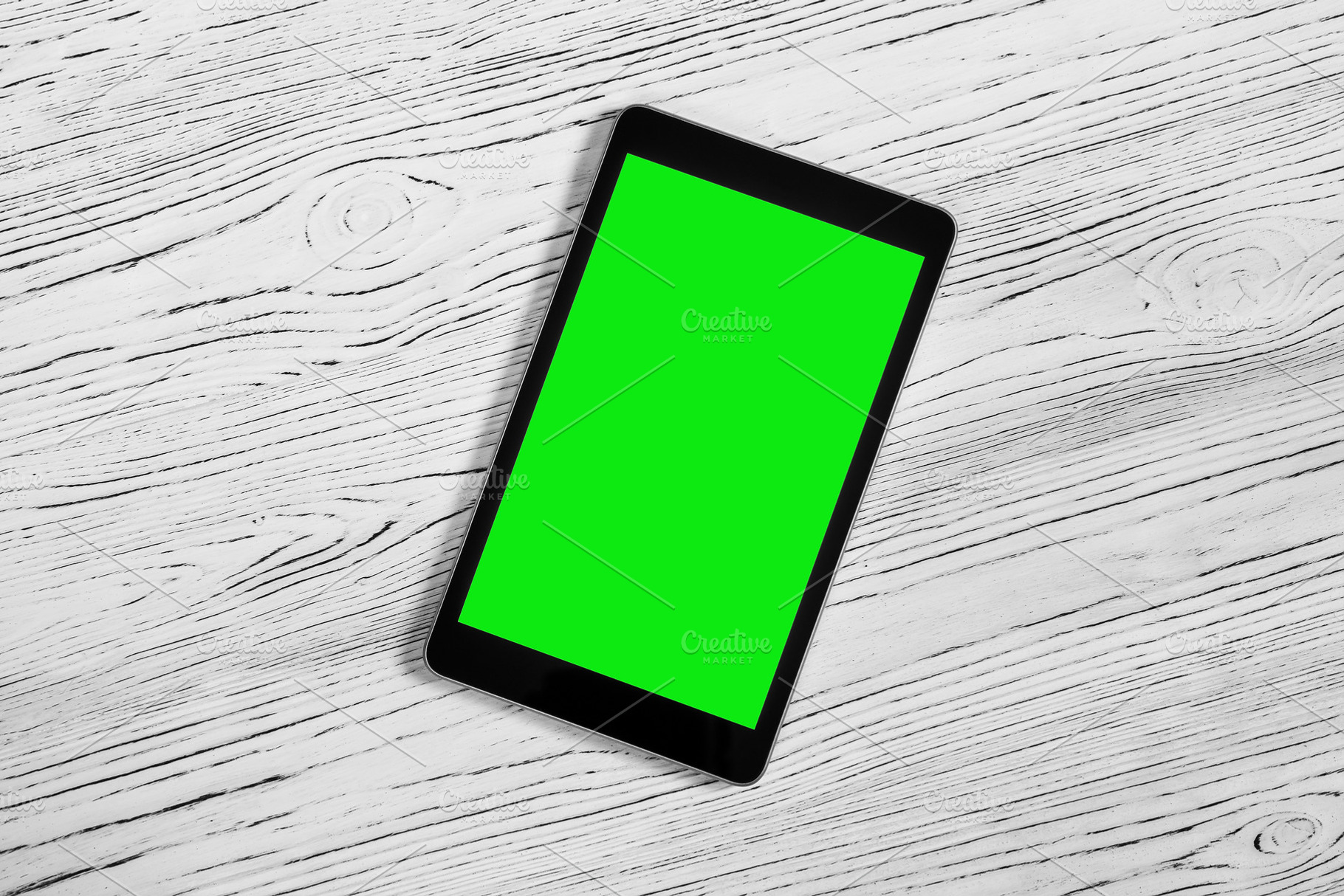 Black tablet with green screen on a wooden table mock up. Copy s, an Abstract Photo by Eugene_Photo