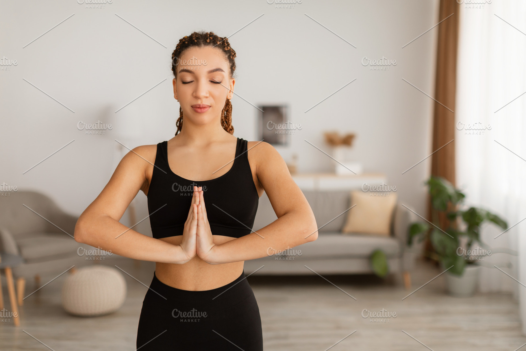 African Female Meditating With Eyes Closed Pressing Hands Together Indoor, a Photo by Prostock-Studio
