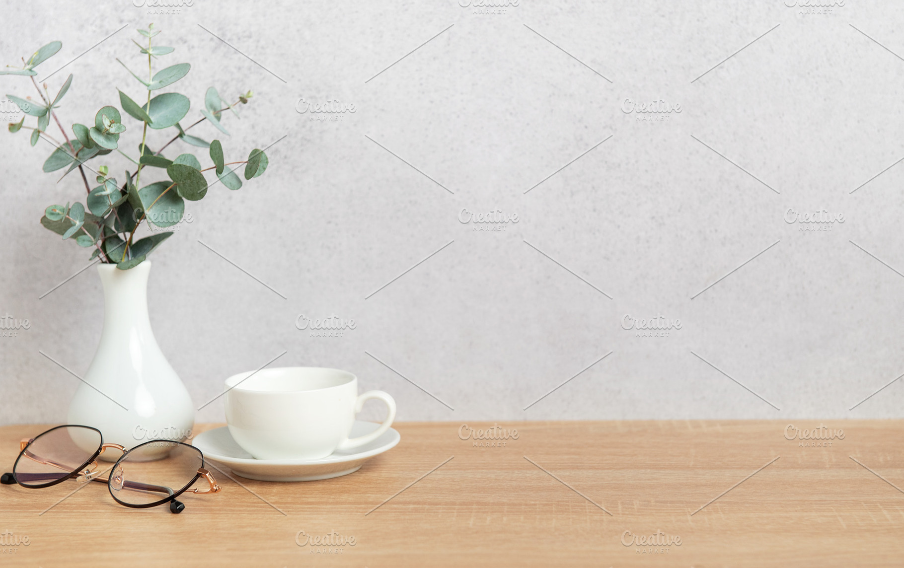 Eucalyptus branches, coffee cup and eyeglasses resting on wooden, a Background Photo by Olena Rudo