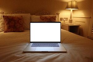 Laptop with blank screen on bed, illuminated by warm bedroom lighting at night,, a Photo by Studio ANNA