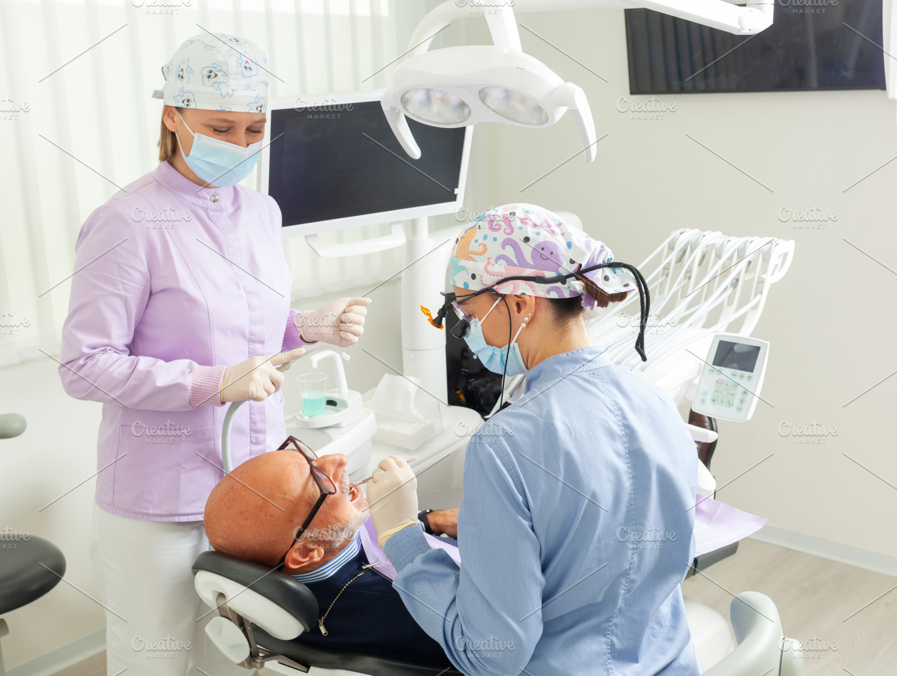 Dentist performing dental checkup on senior man assisted by nurse, a Health & Medical Photo by Antonio Gravante Market