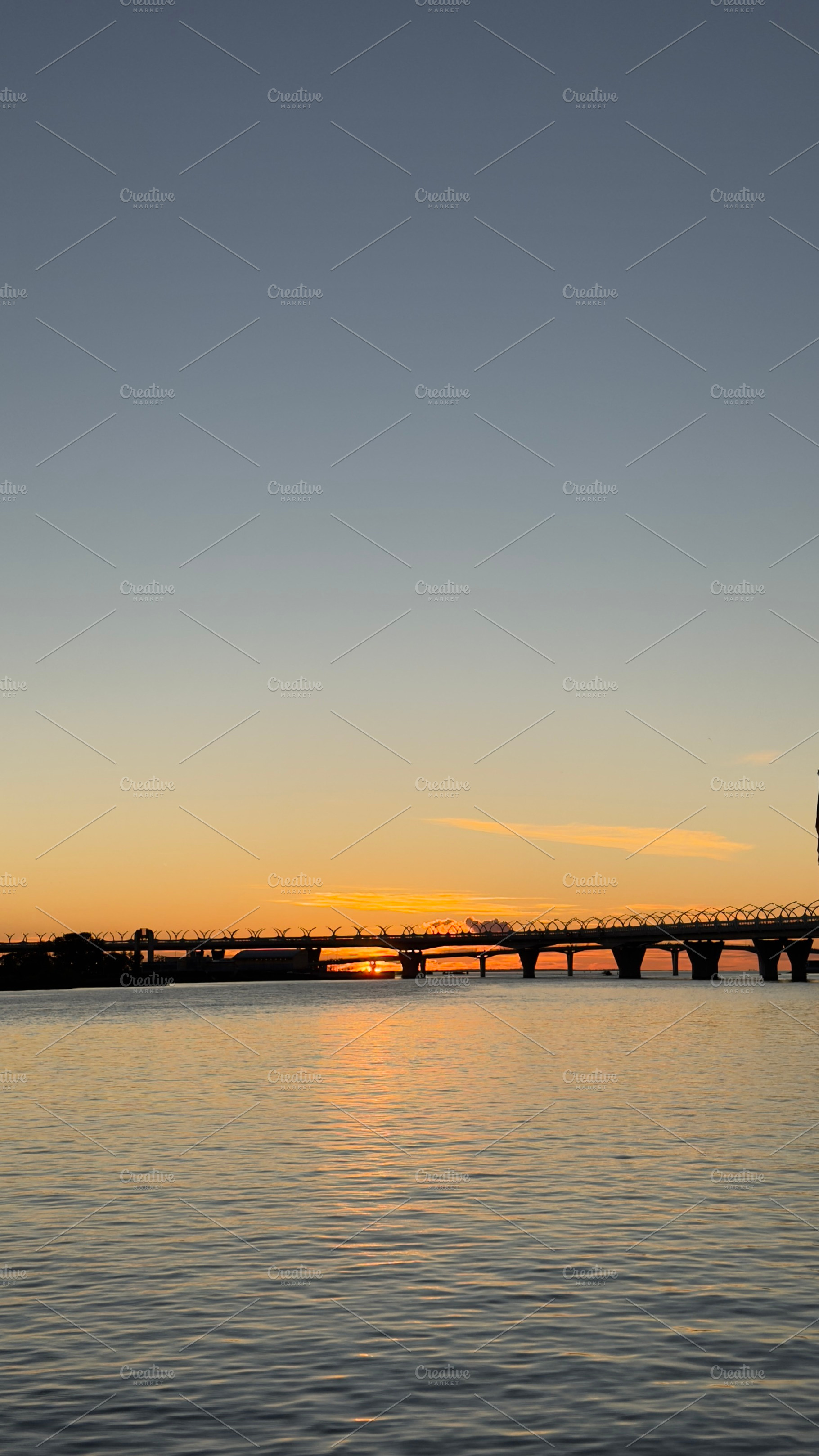 A serene sunset over a calm river, with a bridge silhouetted against the colorf, a Nature Photo by Textures & Backgrounds