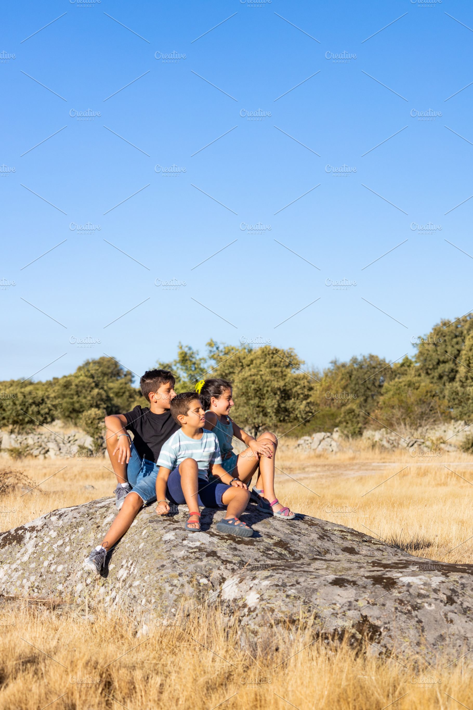 Three kids  with on a top of a rock on their summer vacation, a Person Photo by Cosca