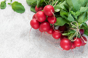 Fresh organic radishes with green leaves on light background, a Food & Drink Photo by Olena Rudo