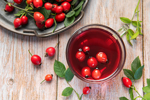 Steaming rosehip tea with fresh rose hips on rustic wooden table, a Food & Drink Photo by Olena Rudo