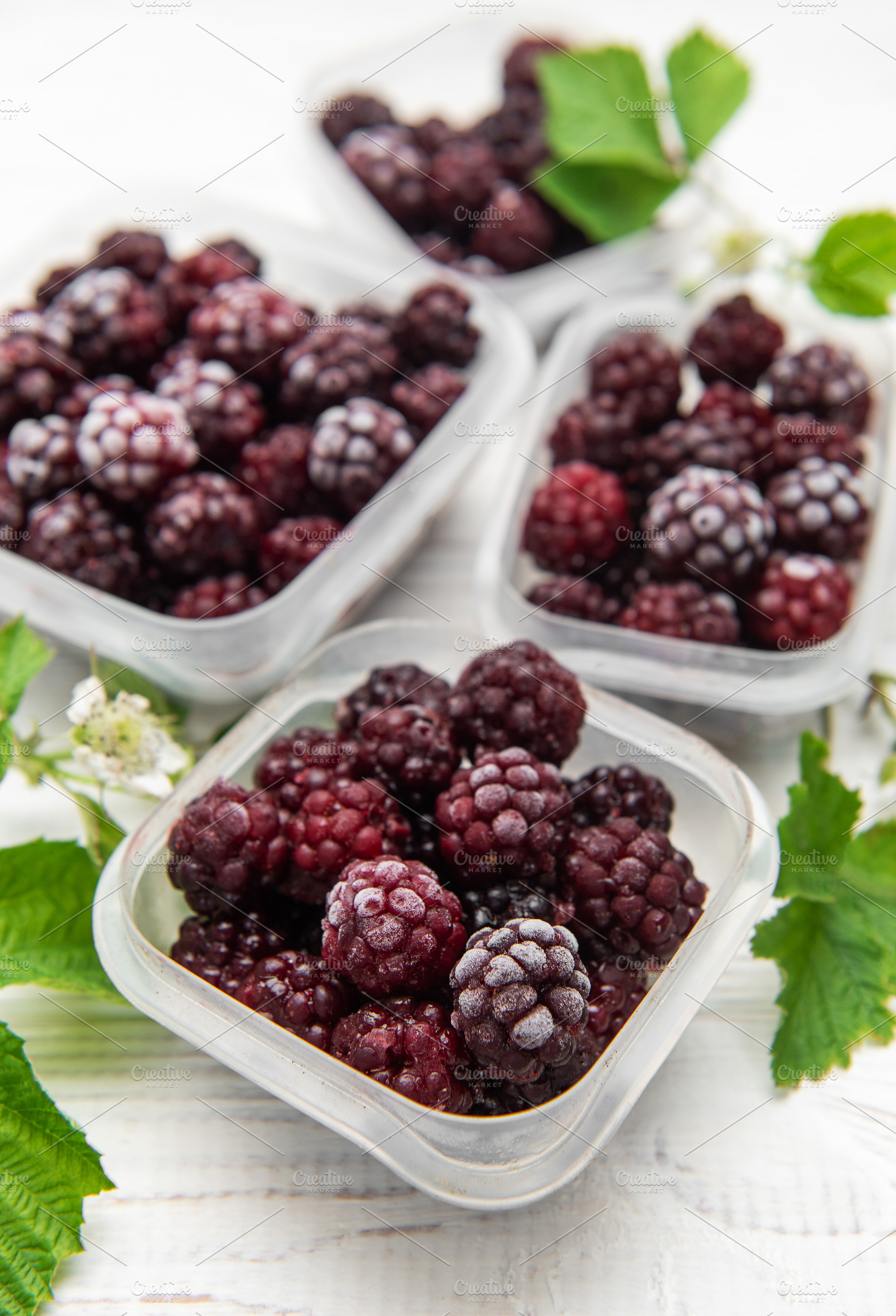 Frozen blackberries in containers on white wooden table, a Food & Drink Photo by Olena Rudo