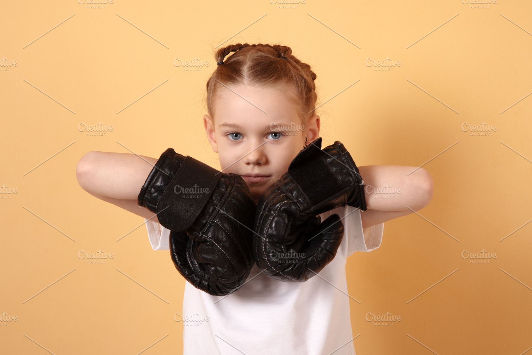 Young girl in white t-shirt wearing black boxing gloves, posing, a Person Photo by Ales Munt
