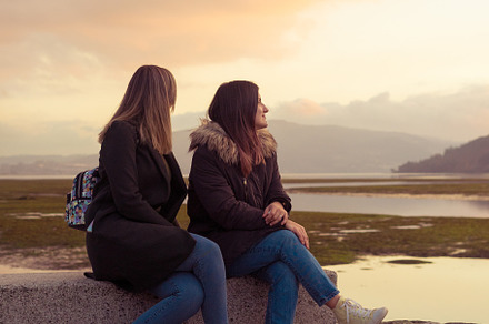 Two female friends sitting on a bench, a Person Photo by rubenchase