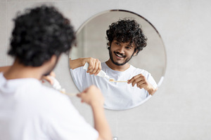 Indian man cleaning teeth in the morning, applying toothpaste on toothbrush, lo, a Person Photo by Prostock-Studio
