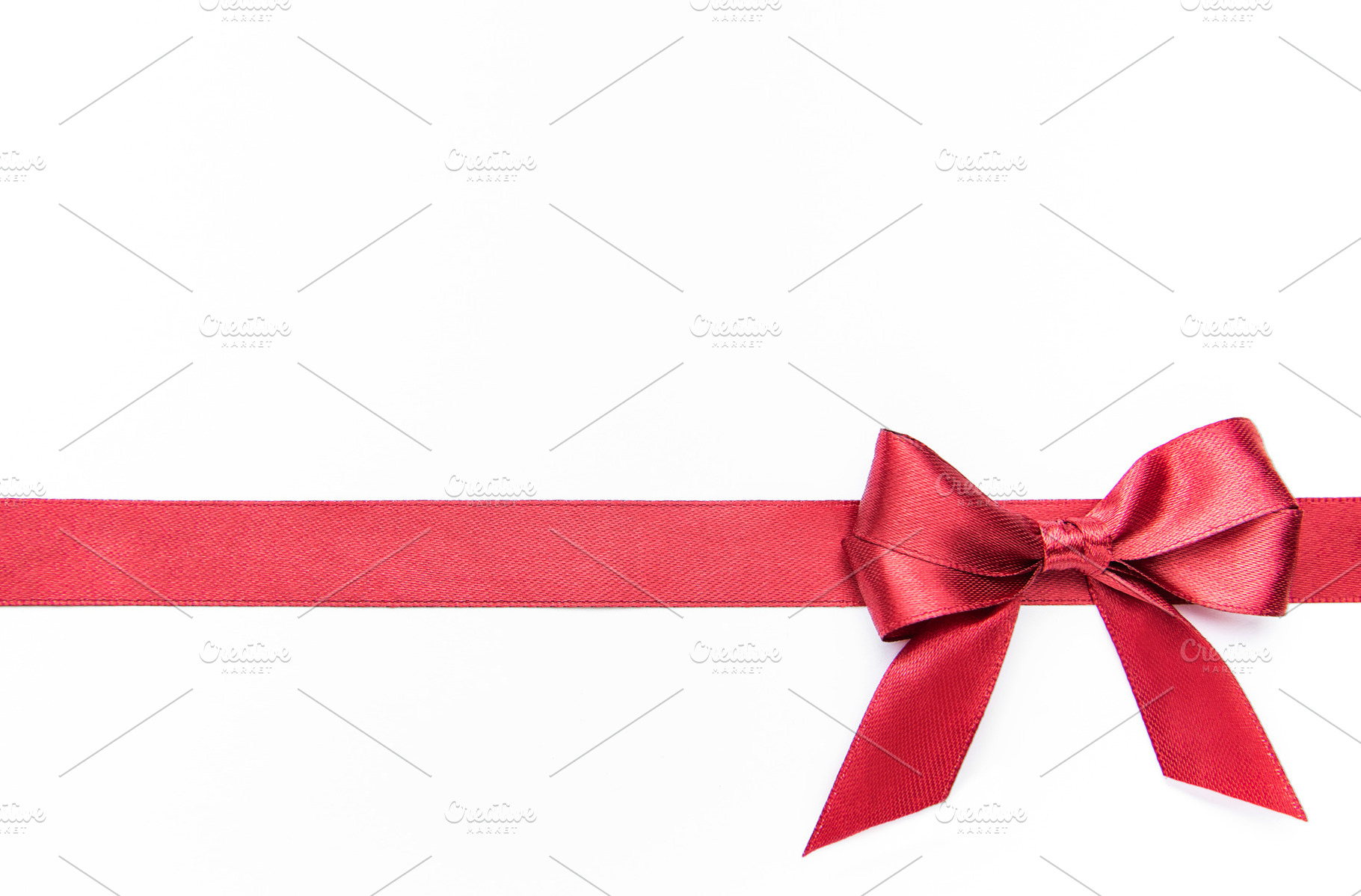 Red ribbon and bow creating festive border on white, a Holiday Photo by Olena Rudo
