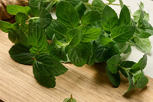 Fresh green mint sprigs lying on  wooden board, a Food & Drink Photo by ndanko