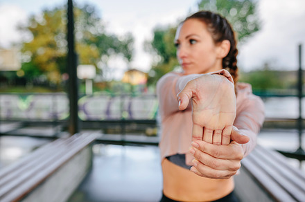 Young female athlete stretching hands and wrists outdoors, a Sports & Recreation Photo by davidpereiras