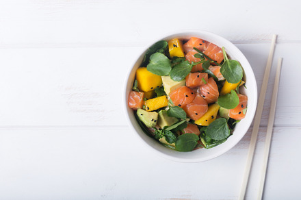Hawaiian poke salad with salmon avocado and vegetables in a bowl on a white, a Food & Drink Photo by zakiroff