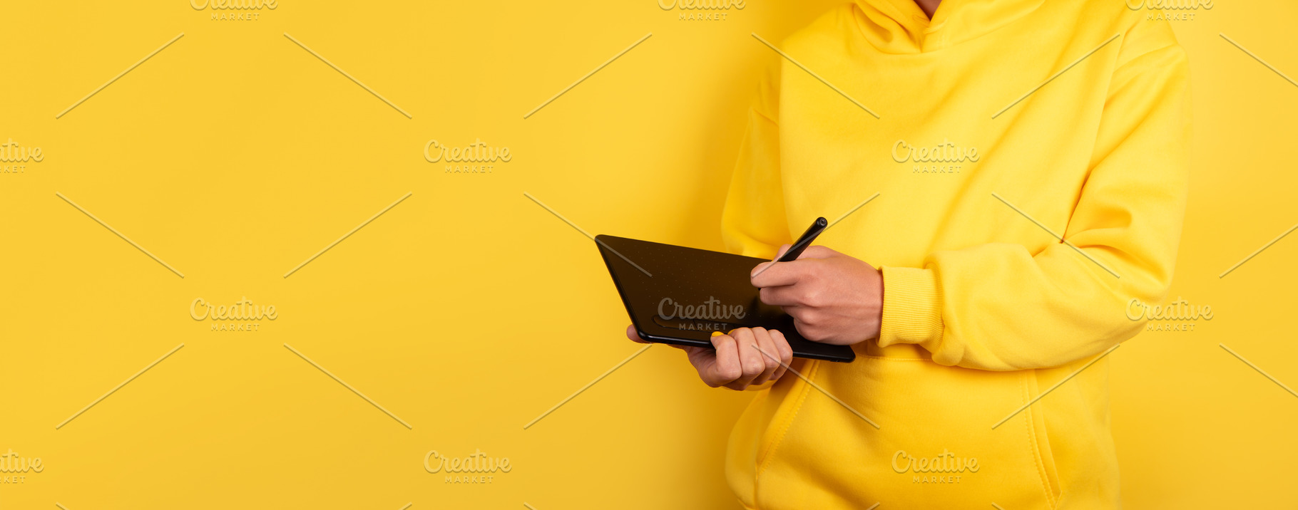 Person in yellow hoodie using digital pen tablet against vibrant, a Technology Photo by Ales Munt