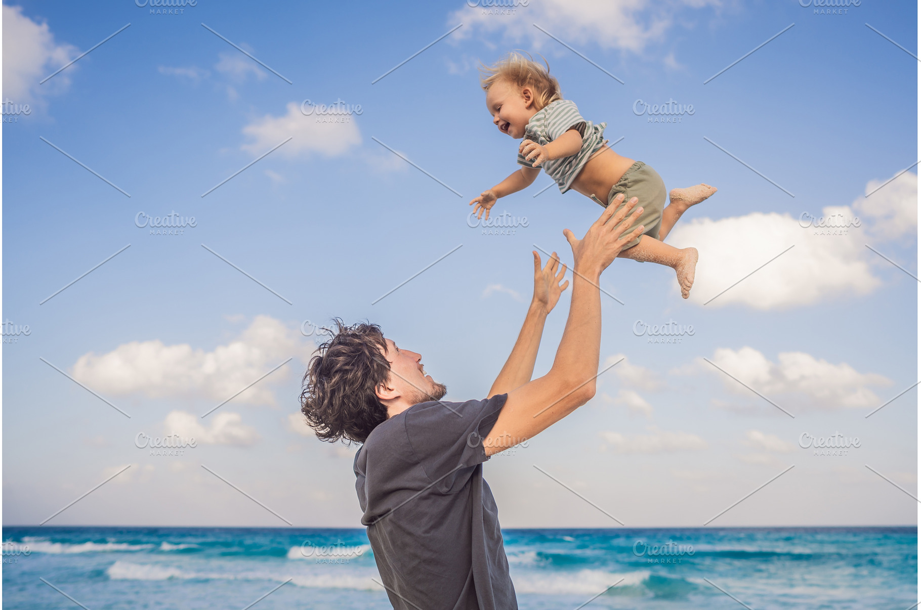 Father playfully lifts his young son, a Holiday Photo by Elizaveta Galitskaya