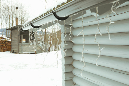 Cozy wooden house with garland in winter season, a Holiday Photo by AtlasStudio PRO