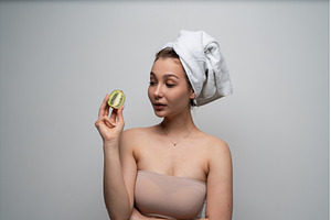 Woman holding half kiwi looking at, a Health & Medical Photo by volodymyrshtun13795