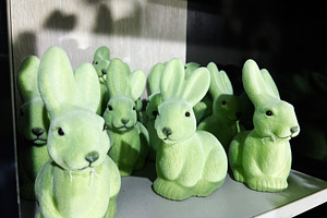 Group of green decorative rabbit figurines displayed on a shelf, a Photo by AS photostudio