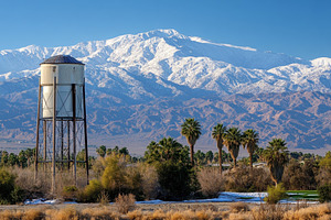 Snow-capped mountains tower over a d, a Photo by Tanuart