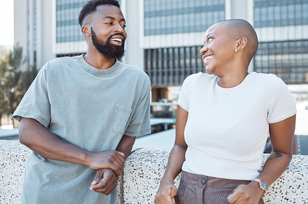 Conversation, black people and happy couple of friends in a city with happiness outdoor. Urban lifestyle, laughing woman and communication by a building with partner and smile from discussion, a Photo by Peopleimages.com