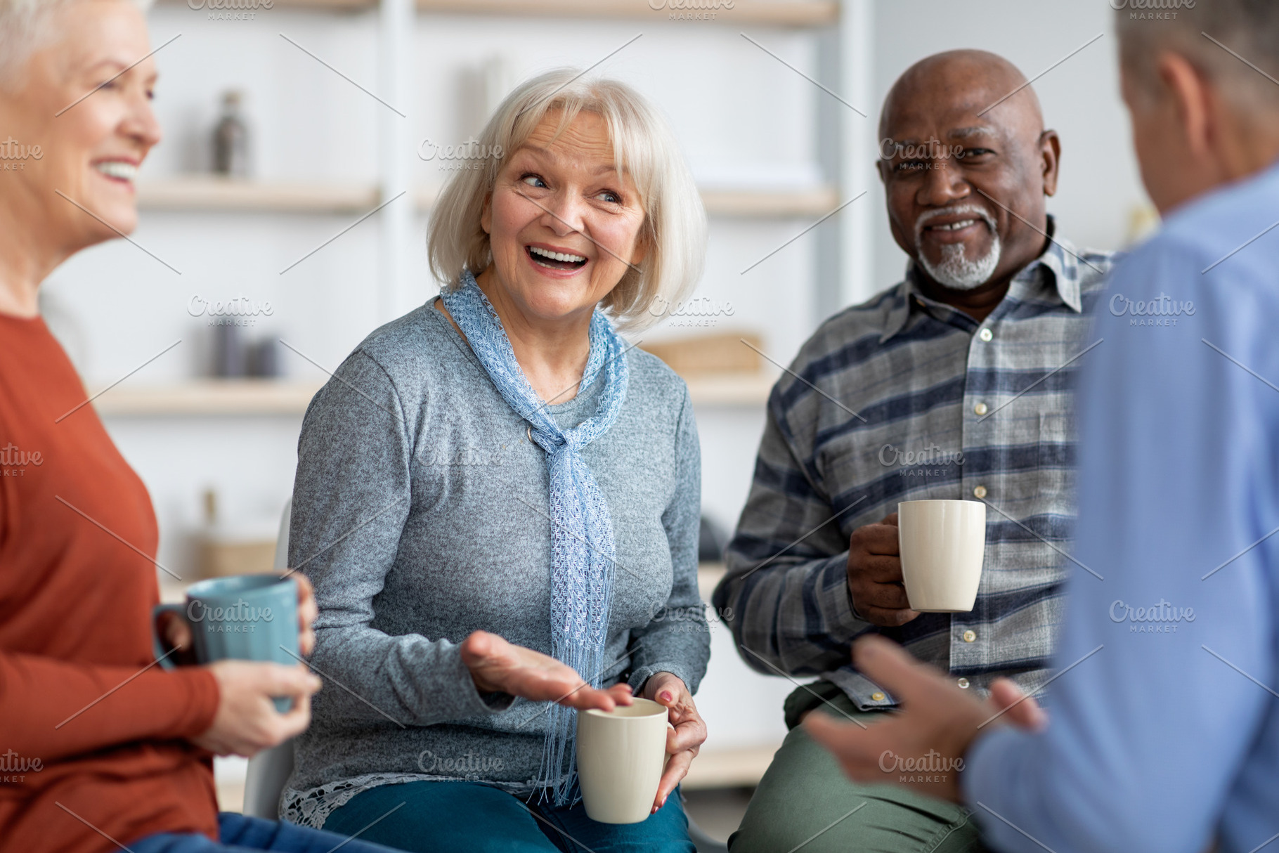 Multiracial group of positive elderly people drinking tea, chatting, a Photo by Prostock-Studio
