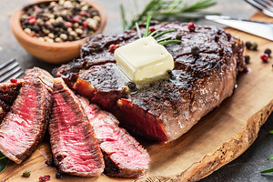 Grilled medium rare ribeye steak slices with melting butter on w, a Food & Drink Photo by Volff