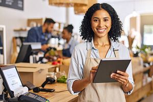 Woman holding tablet while looking at camera at small business e, a Business Photo by DanFLCreativo