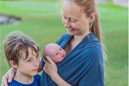 Mom walks with a newborn in a sling